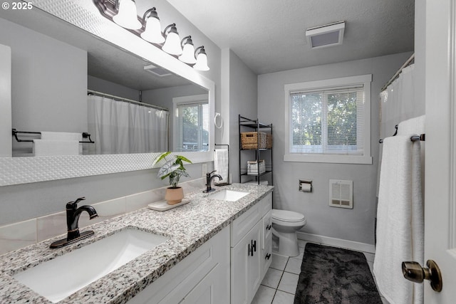 bathroom with a textured ceiling, vanity, heating unit, tile patterned flooring, and toilet