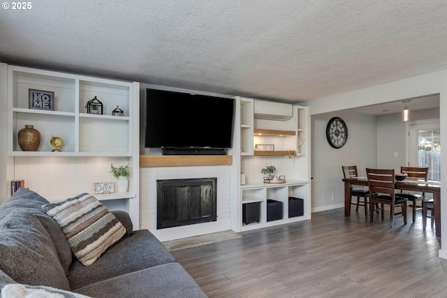 living room with wood-type flooring, a textured ceiling, and a wall mounted AC