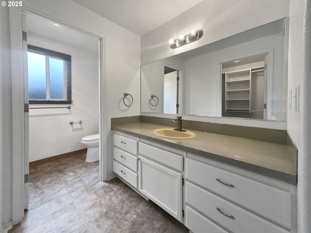 bathroom with toilet, vanity, and baseboards