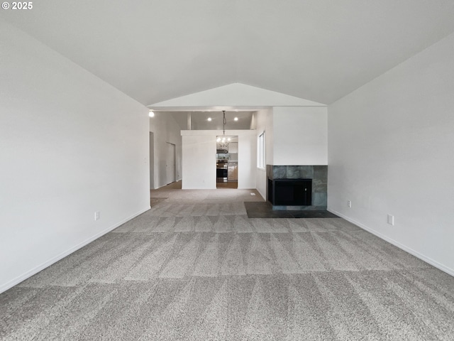 unfurnished living room featuring light carpet, a tiled fireplace, baseboards, and lofted ceiling