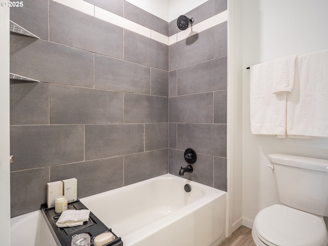 bathroom with tiled shower / bath, wood-type flooring, and toilet