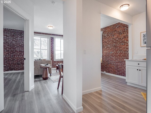 hall featuring brick wall and light hardwood / wood-style flooring