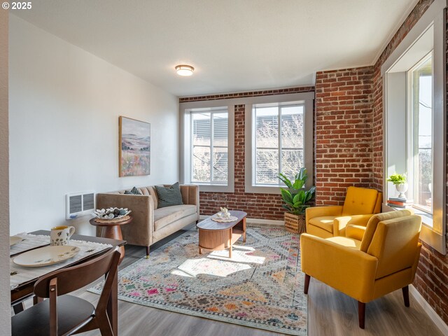 living area featuring brick wall and wood-type flooring