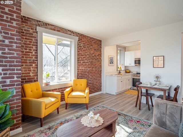 living room featuring brick wall, sink, and light wood-type flooring