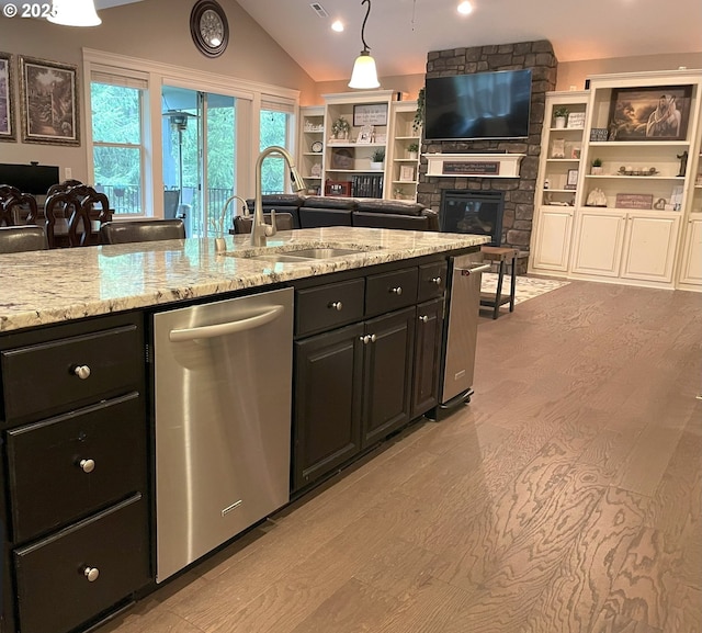 kitchen featuring a fireplace, dishwasher, a sink, lofted ceiling, and open floor plan