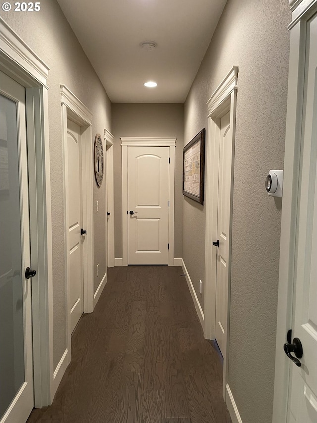hall with baseboards, dark wood-style flooring, and a textured wall