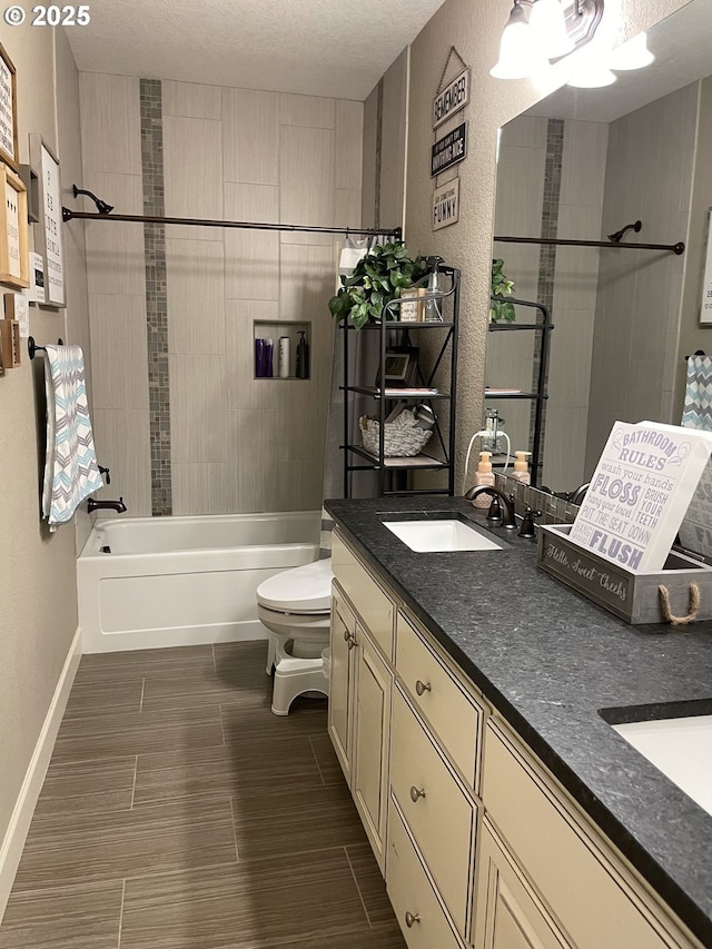 bathroom featuring a sink, bathtub / shower combination, double vanity, toilet, and a textured ceiling