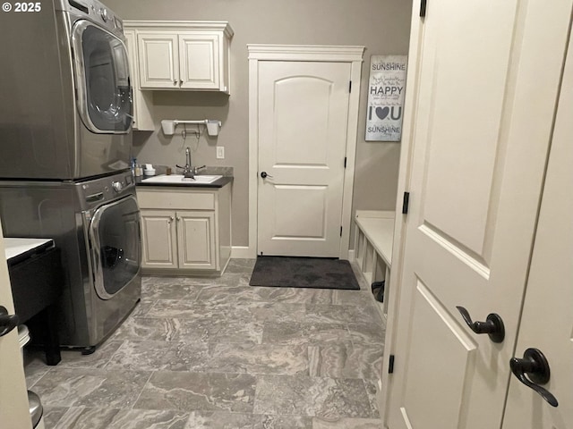laundry area featuring cabinet space, stacked washer / drying machine, and a sink