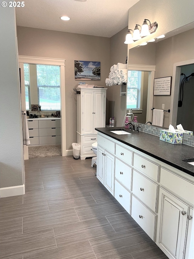 full bath featuring a sink, baseboards, and a healthy amount of sunlight