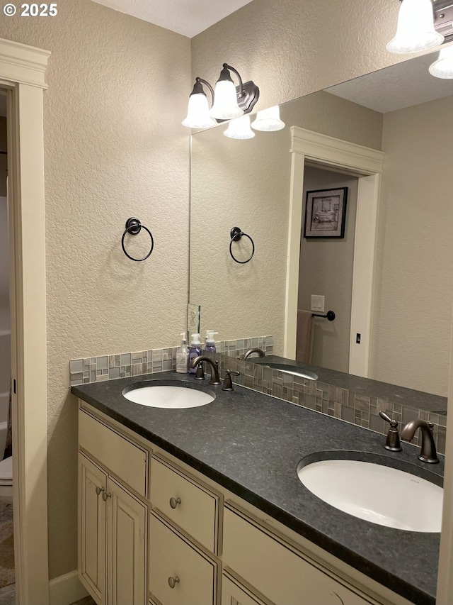 bathroom with a sink, a textured wall, and double vanity
