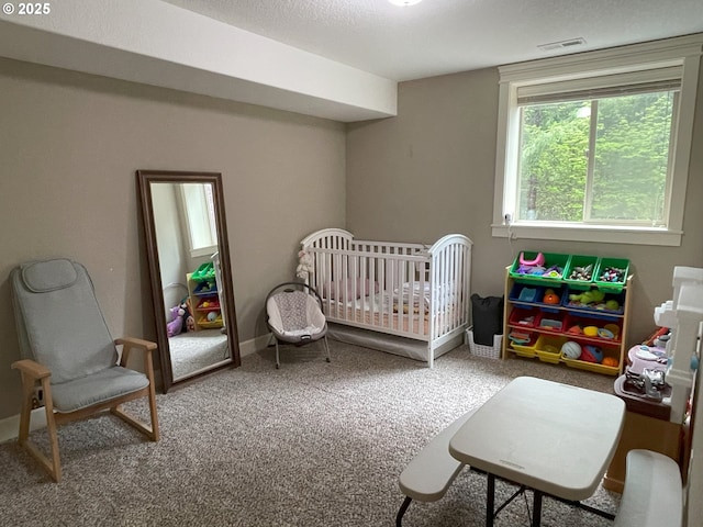 bedroom with carpet floors, a nursery area, and visible vents