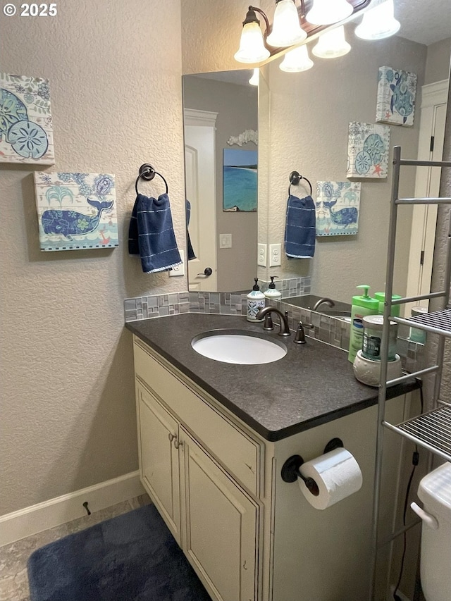 bathroom with vanity, a textured wall, baseboards, and a notable chandelier