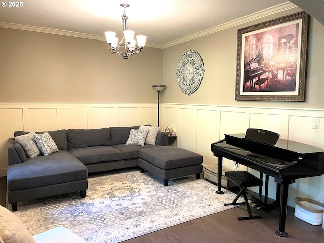 living area featuring an inviting chandelier, crown molding, wainscoting, a decorative wall, and dark wood finished floors