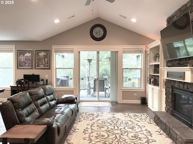 living area featuring ceiling fan, a fireplace, wood finished floors, vaulted ceiling, and visible vents