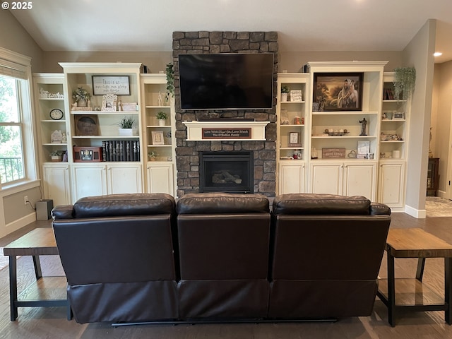 living area with a stone fireplace, a healthy amount of sunlight, and wood finished floors