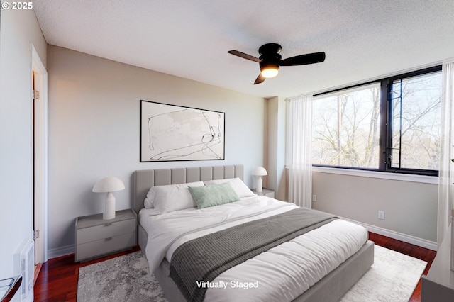 bedroom with a textured ceiling, ceiling fan, and dark hardwood / wood-style floors