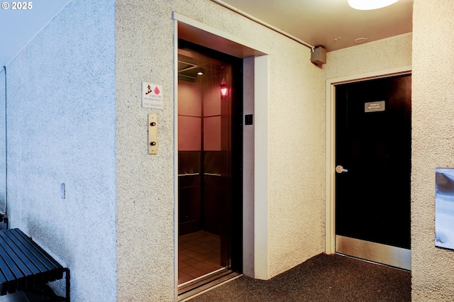 hallway with elevator and carpet floors