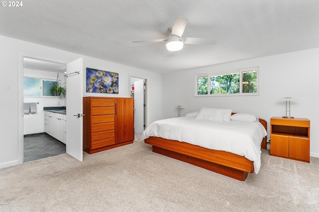 bedroom featuring carpet, connected bathroom, ceiling fan, and a textured ceiling