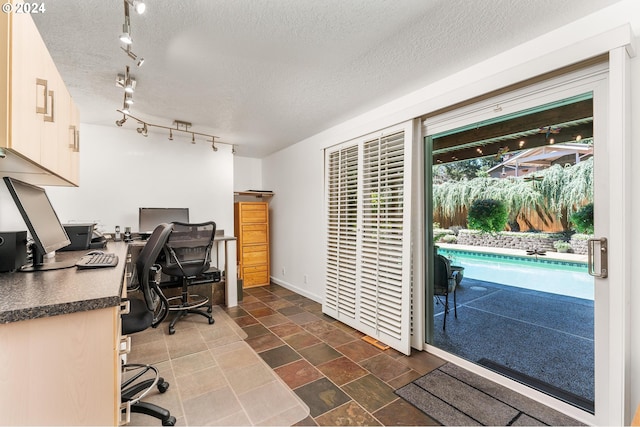 office space featuring a textured ceiling, stone finish flooring, and baseboards