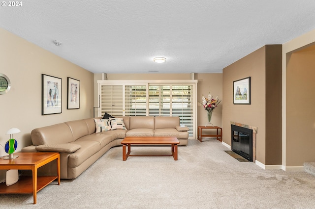 living area with a textured ceiling, carpet floors, a tiled fireplace, and baseboards