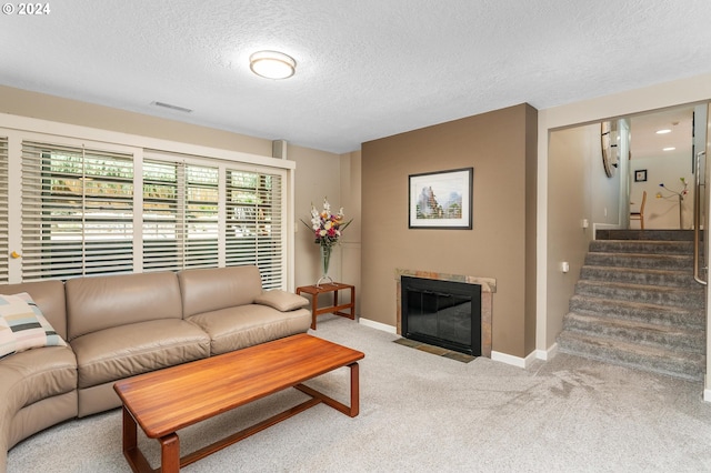 living room with visible vents, baseboards, a fireplace with flush hearth, carpet, and stairs