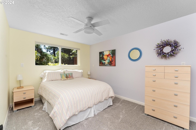 bedroom with light carpet, baseboards, visible vents, ceiling fan, and a textured ceiling