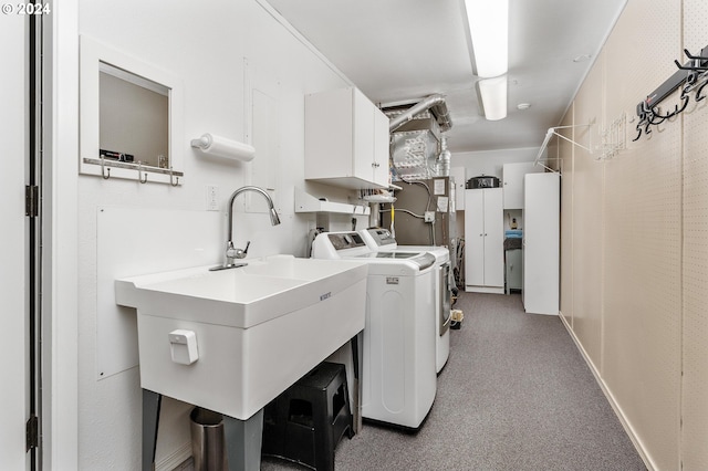 laundry room with a sink, carpet flooring, washing machine and dryer, and cabinet space