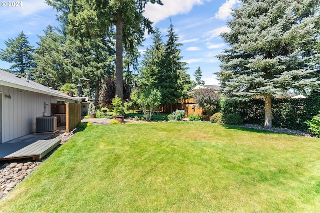 view of yard with fence, a wooden deck, and central air condition unit