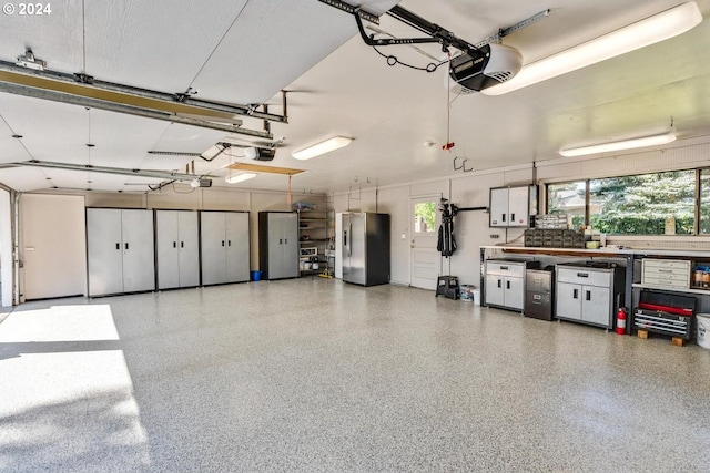 garage with a garage door opener and stainless steel refrigerator with ice dispenser