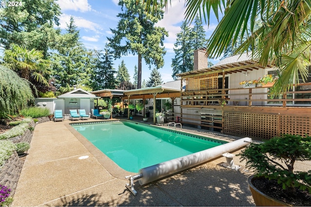 view of pool featuring an outbuilding, a patio area, a wooden deck, and a covered pool