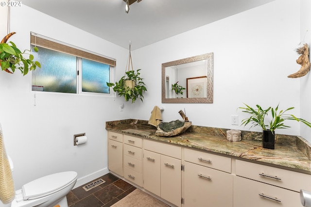 bathroom featuring toilet, baseboards, visible vents, and vanity