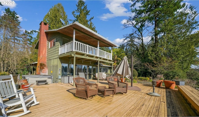 rear view of property featuring a balcony, a chimney, and a hot tub