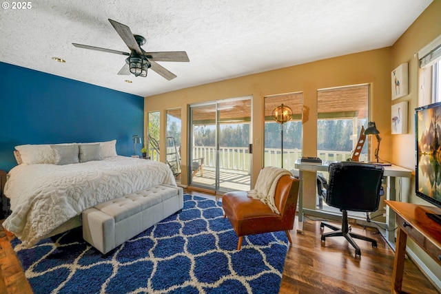 bedroom with access to outside, multiple windows, wood finished floors, and a textured ceiling