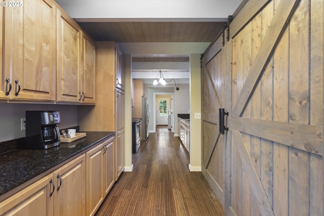 28825 SW Grahams Ferry Rd, Wilsonville, OR 97070 - kitchen with a barn door, dark wood-type flooring, dark stone counters, and freestanding refrigerator
