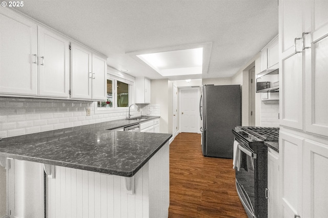 6516 SW Locust St, Portland, OR 97223 - kitchen featuring appliances with stainless steel finishes, white cabinets, dark wood-style floors, decorative backsplash, and a peninsula