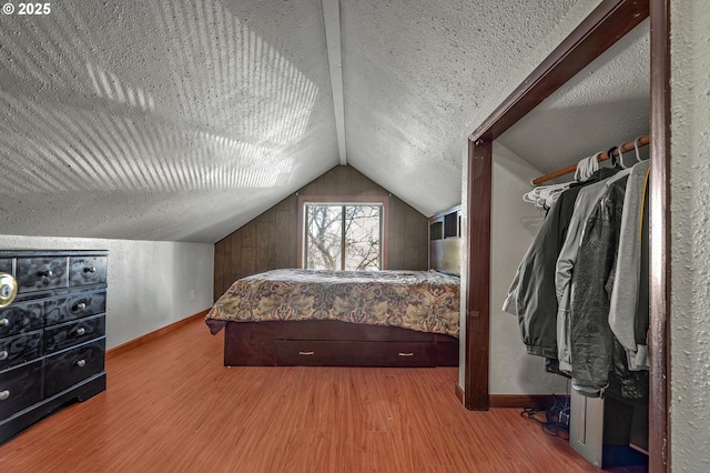 bedroom featuring a textured ceiling, lofted ceiling, and hardwood / wood-style floors