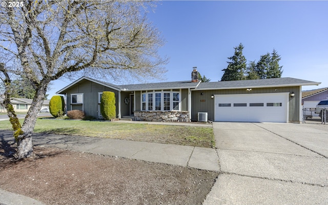 ranch-style home featuring a front yard, cooling unit, driveway, a chimney, and a garage