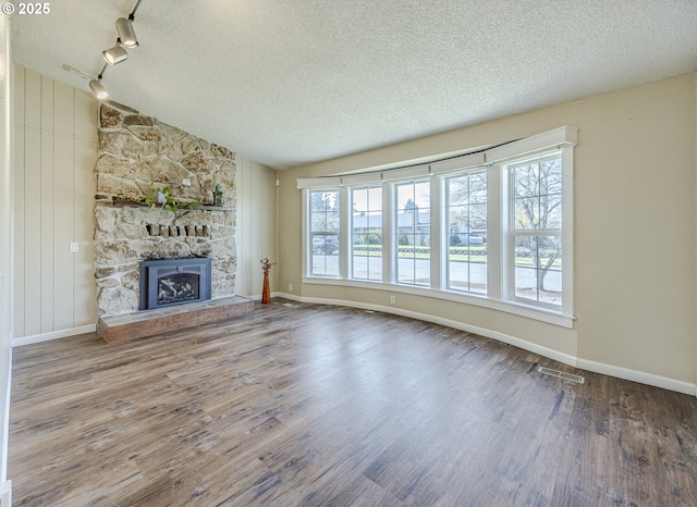 unfurnished living room with a stone fireplace, plenty of natural light, lofted ceiling, and wood finished floors