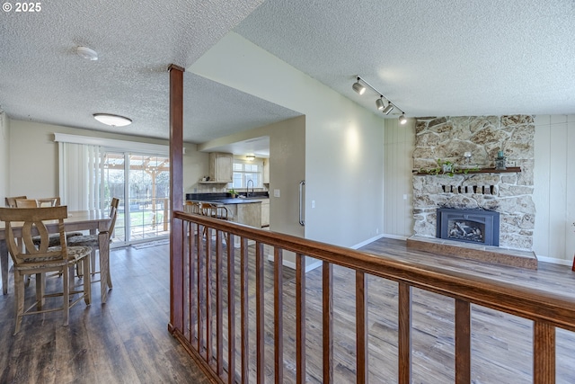 interior space featuring baseboards, a fireplace, rail lighting, wood finished floors, and a textured ceiling