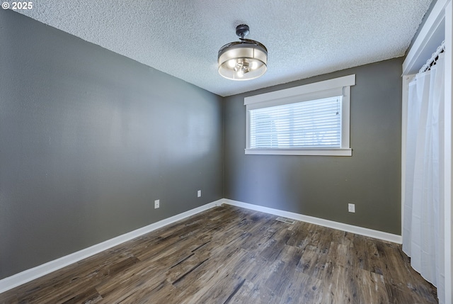 unfurnished bedroom with visible vents, baseboards, dark wood-type flooring, and a textured ceiling