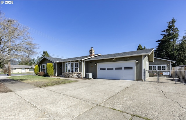 view of front of house with central AC unit, fence, an attached garage, a chimney, and concrete driveway