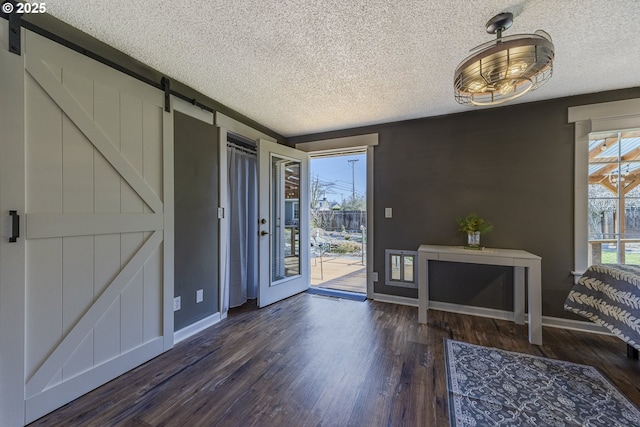 entryway featuring baseboards, a textured ceiling, a barn door, and wood finished floors