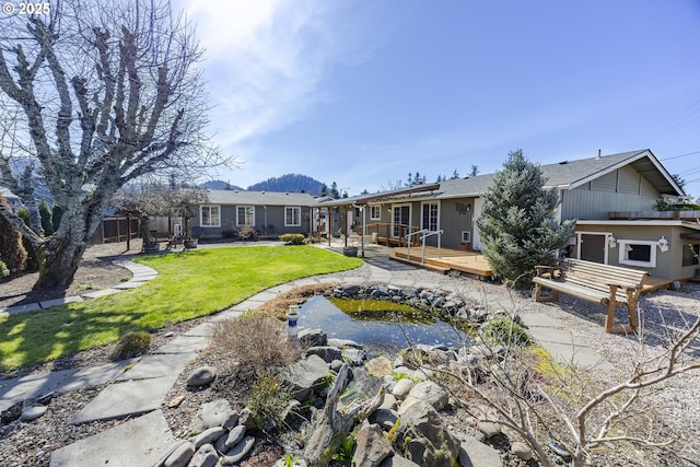 rear view of house featuring a lawn and a deck