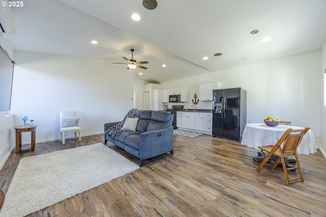 living area featuring a wall mounted AC, wood finished floors, recessed lighting, lofted ceiling, and ceiling fan