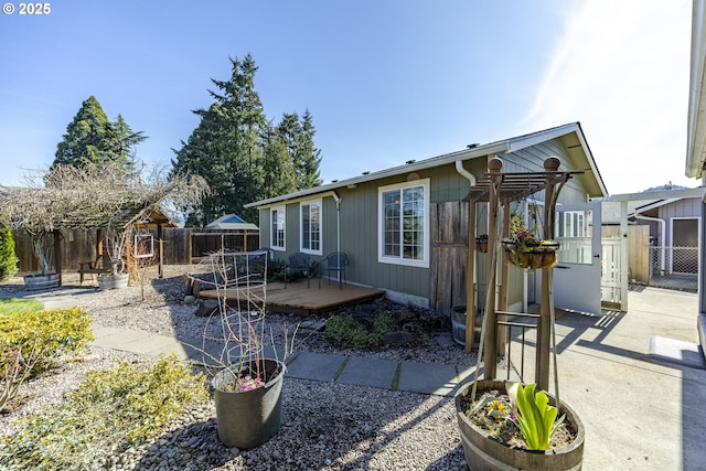 back of property with fence and a wooden deck