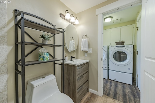 bathroom with visible vents, toilet, wood finished floors, separate washer and dryer, and vanity