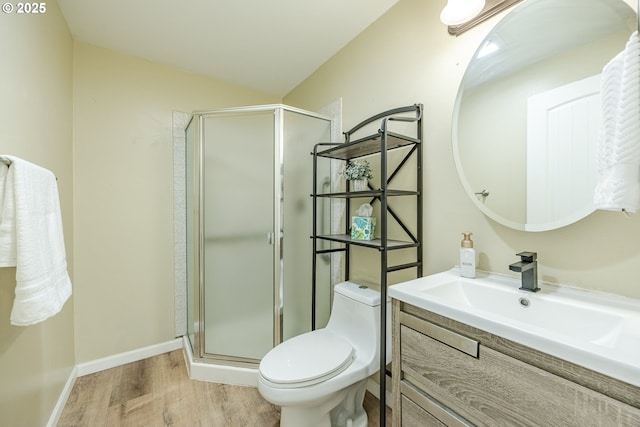 bathroom with a stall shower, toilet, vanity, and wood finished floors