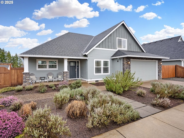 craftsman-style house featuring board and batten siding, fence, concrete driveway, a garage, and stone siding