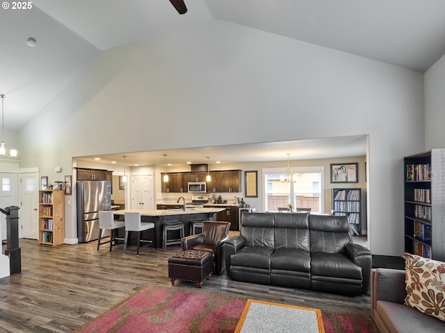 living room featuring a chandelier, high vaulted ceiling, and dark wood-type flooring