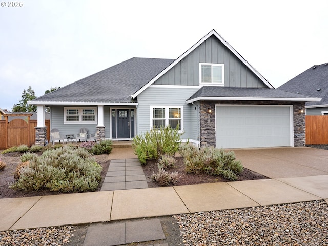 craftsman house featuring driveway, fence, board and batten siding, a shingled roof, and a garage